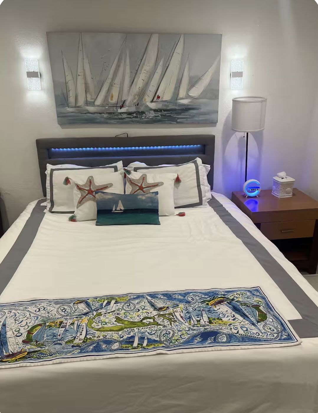 King bed with white linens, sailing painting above and a Bermuda map runner