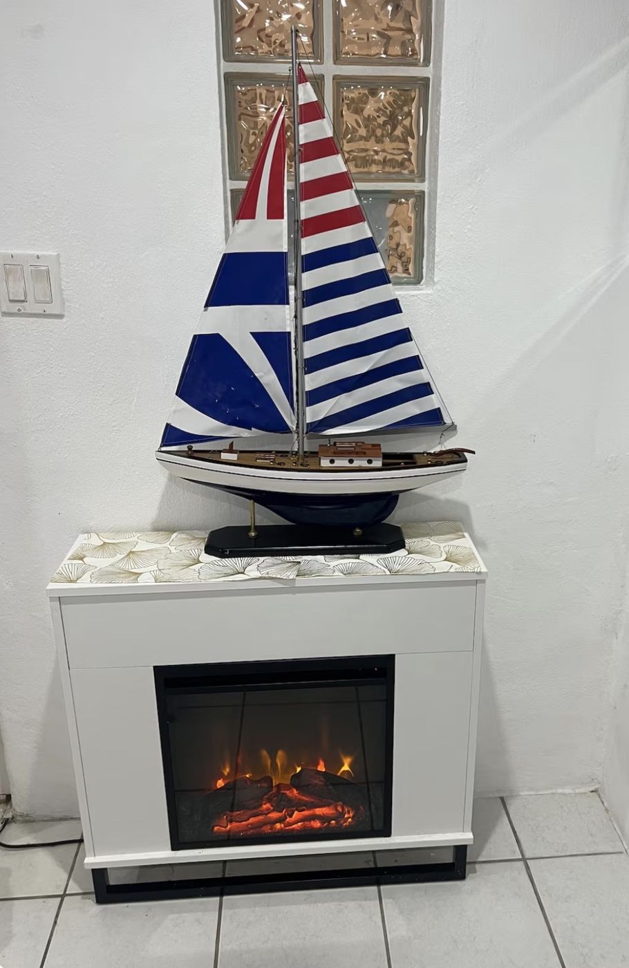 Electric fireplace with a striped model sailboat on top