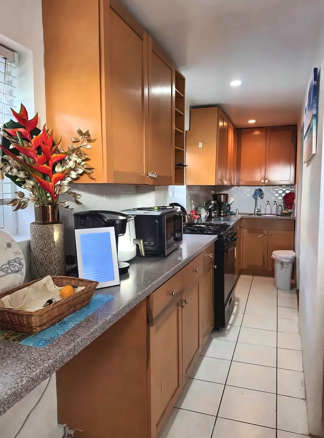 Galley kitchen with wood cabinets, gas range, microwave and air fryer