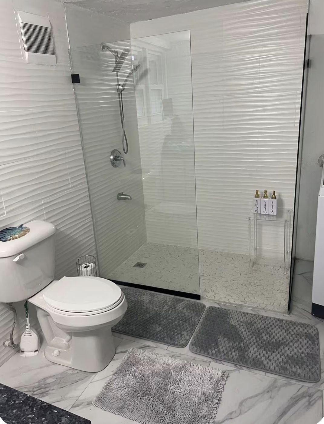 Walk-in glass shower with white wave tiles and marble floor