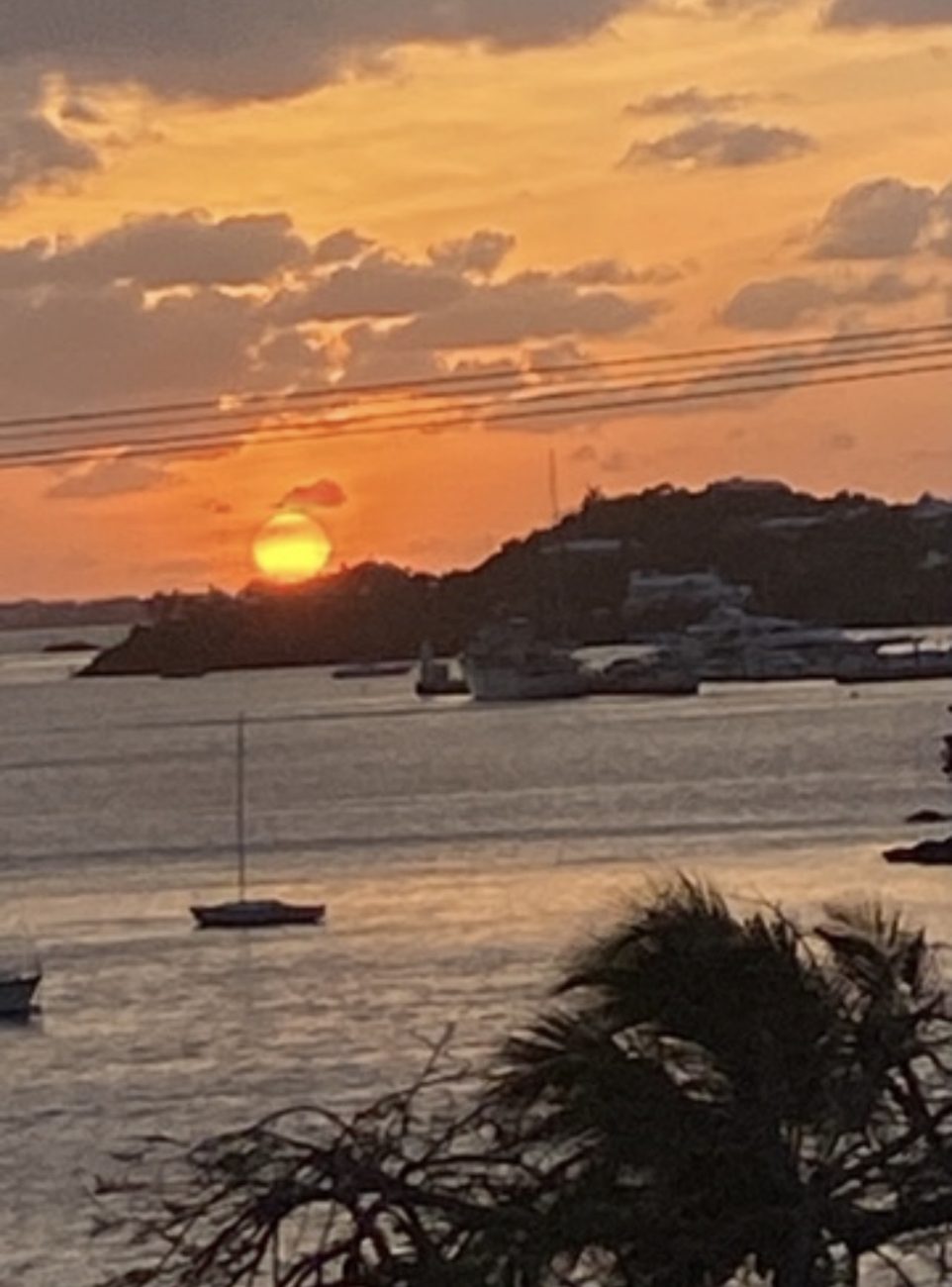 Orange sun setting over the harbour behind a sailboat